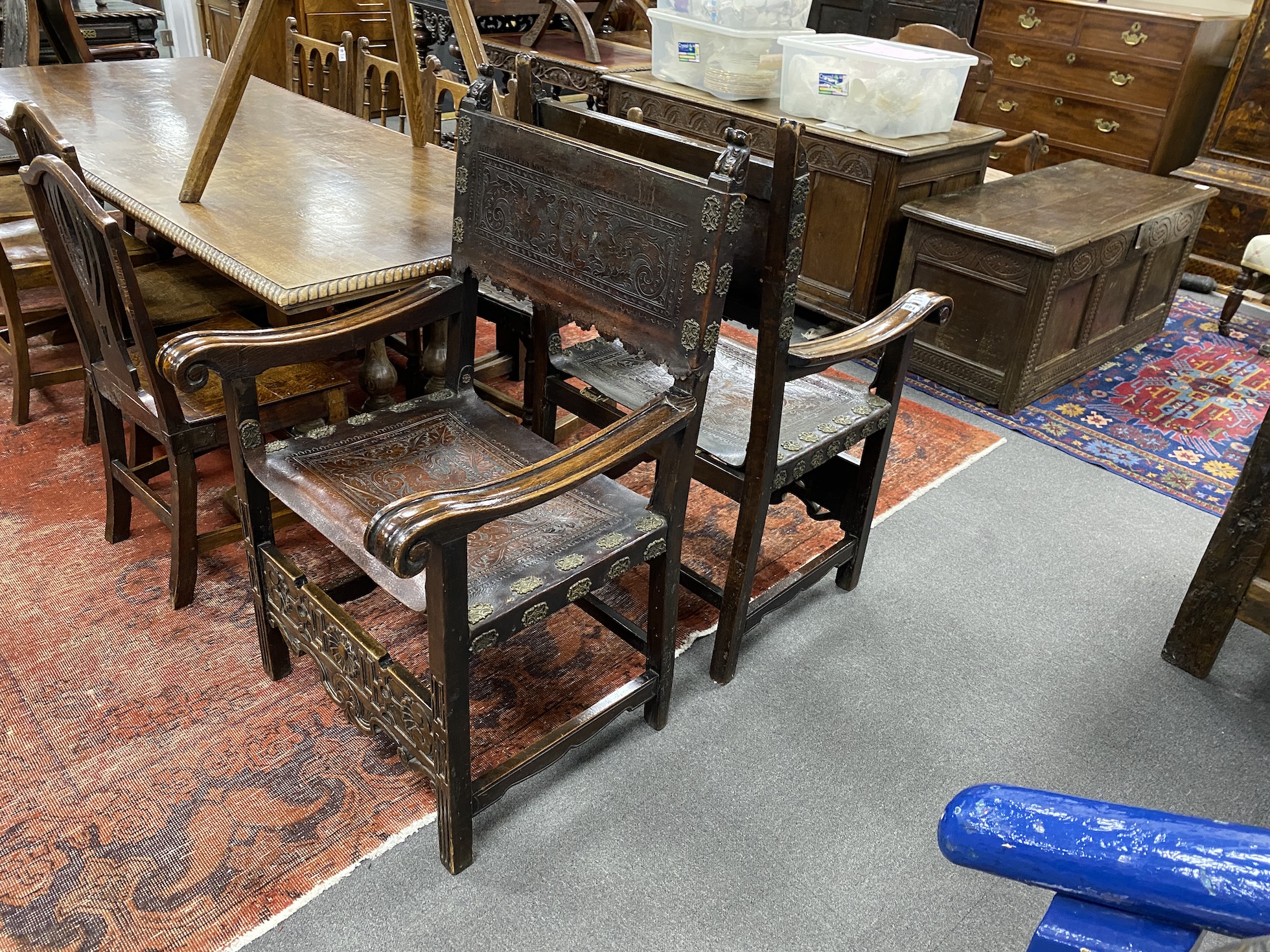 A pair of carved and tooled leather continental elbow chairs, width 68cm, depth 60cm, height 113cm